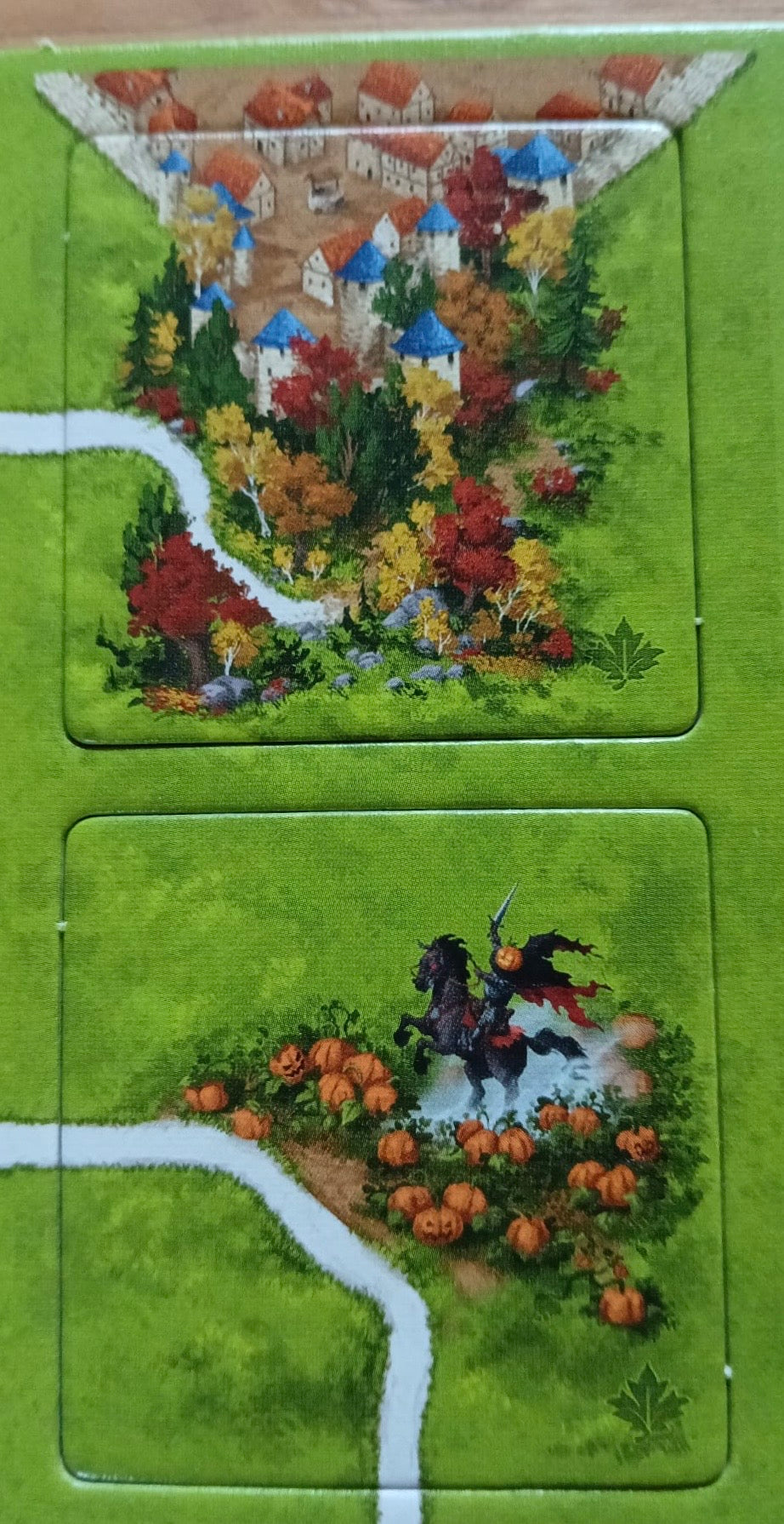 Another view of 2 more of the included tiles, with one showing an equine statue with a pumpkin head in this Autumn mini expansion for the Carcassonne board game.