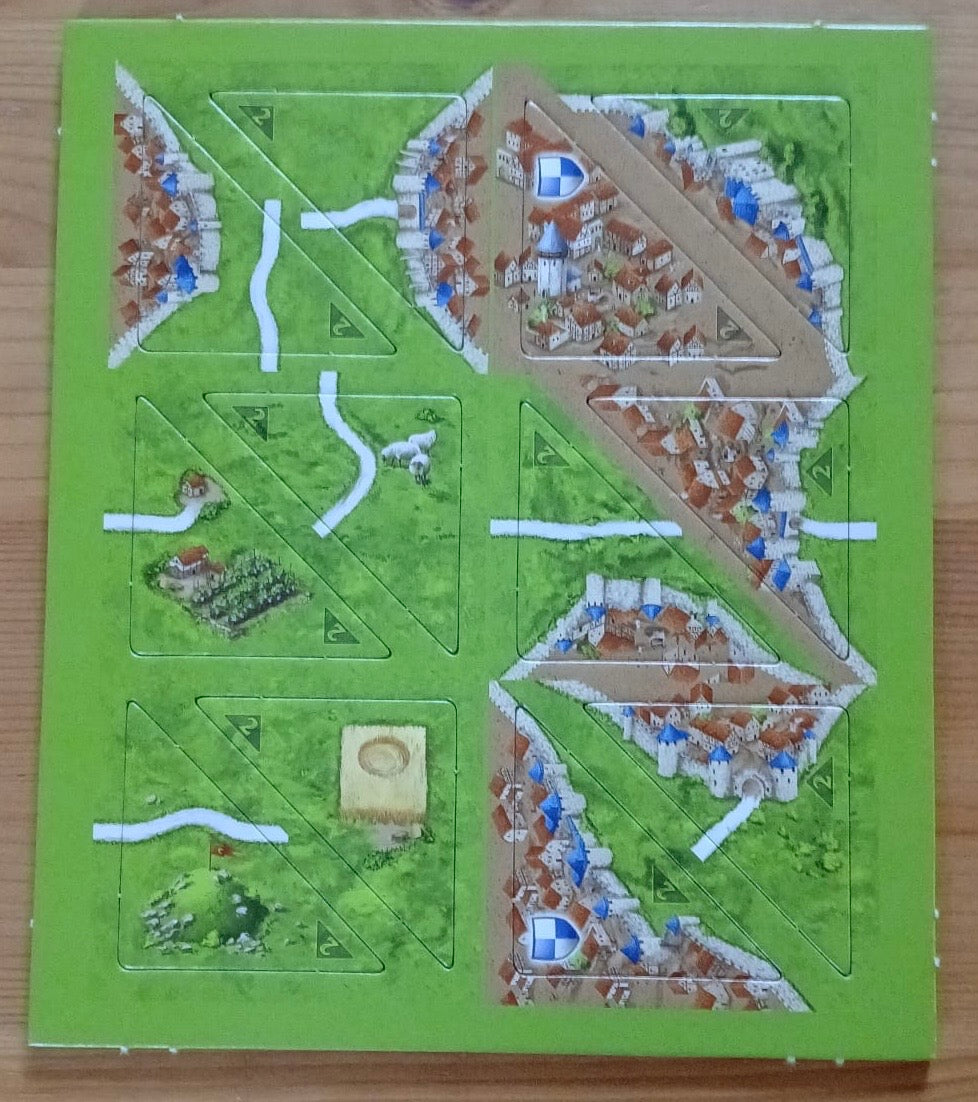 View of 12 of the half-sized tiles, featuring cities and roads, that make up this Halflings 1 & 2 mini expansion for the Carcassonne board game.