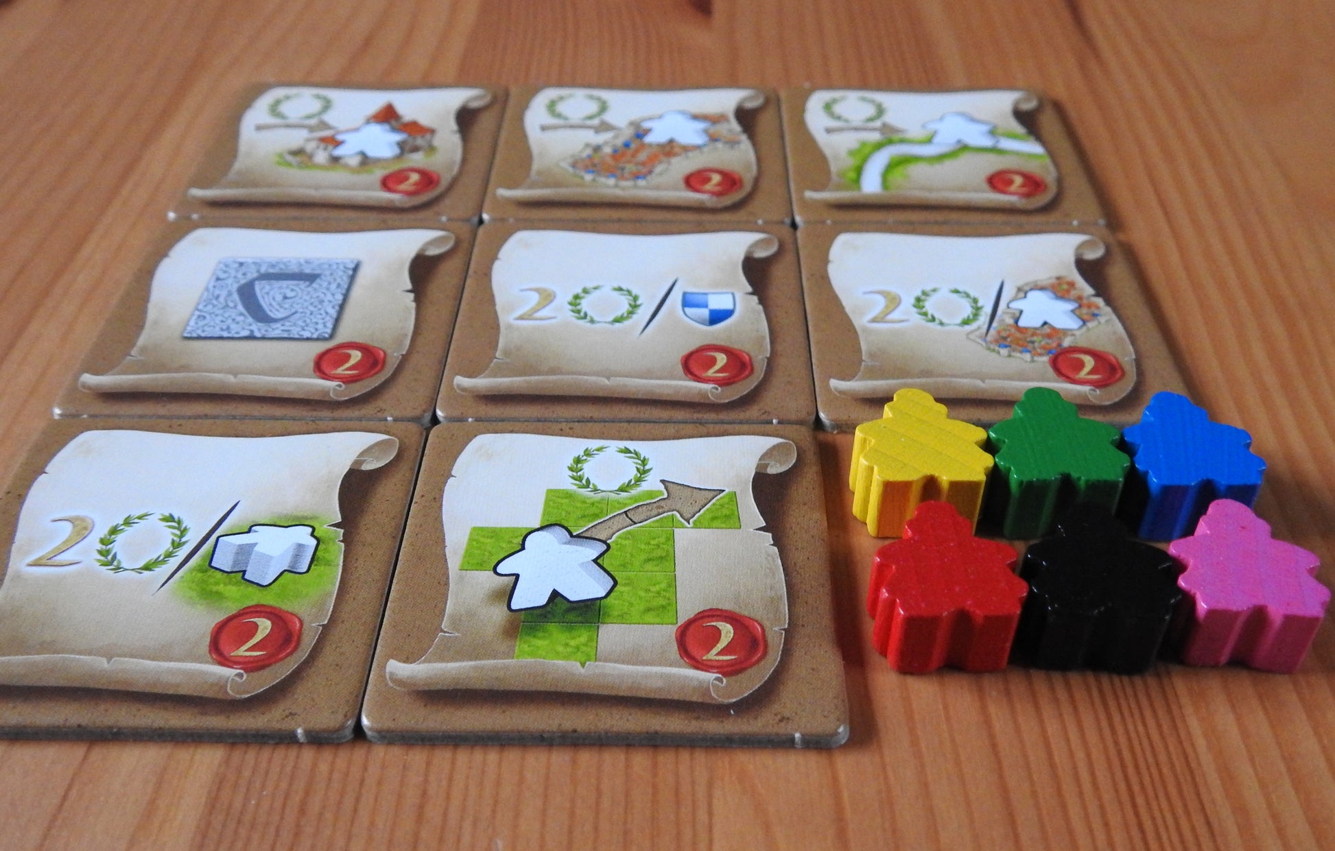 Close up of the tiles and the wooden mini messenger figures in their 6 colours: blue, green, black, red, yellow and pink.