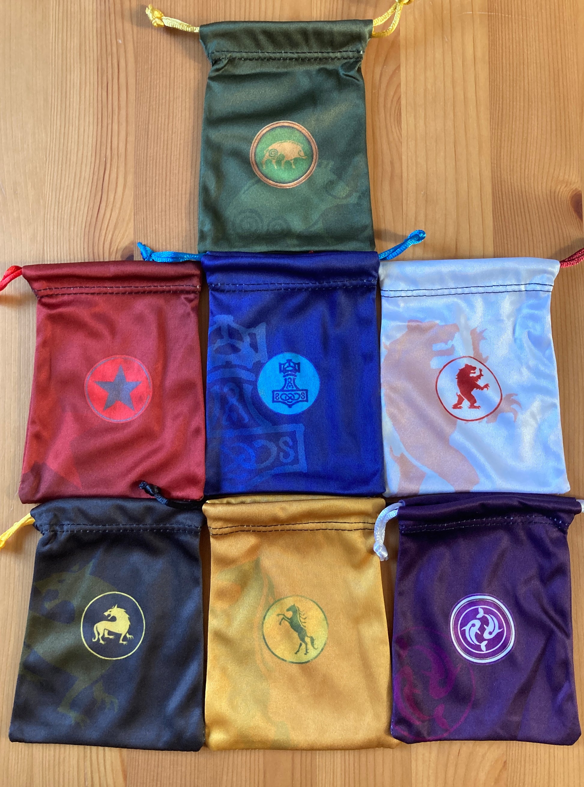 View of all 7 of the included colourful faction bags in this accessory for Scythe.
