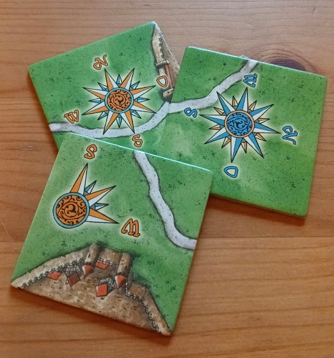 View of t3 of the included tiles, with their blue and orange windrose compasses in this Windrose I mini expansion for the Carcassonne board game.