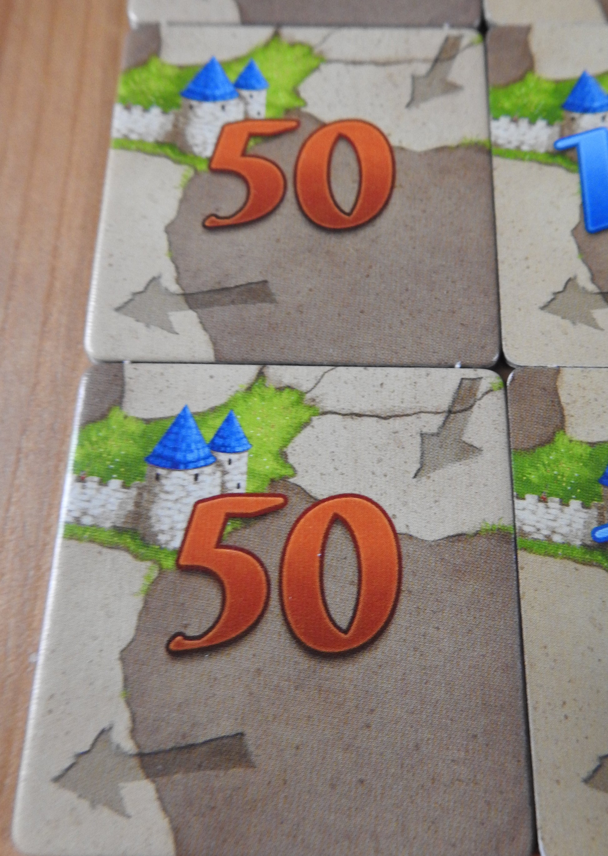 A close-up of some of the '50' tiles that come with this 6 Extra Scoring Tiles accessory for Carcassonne.