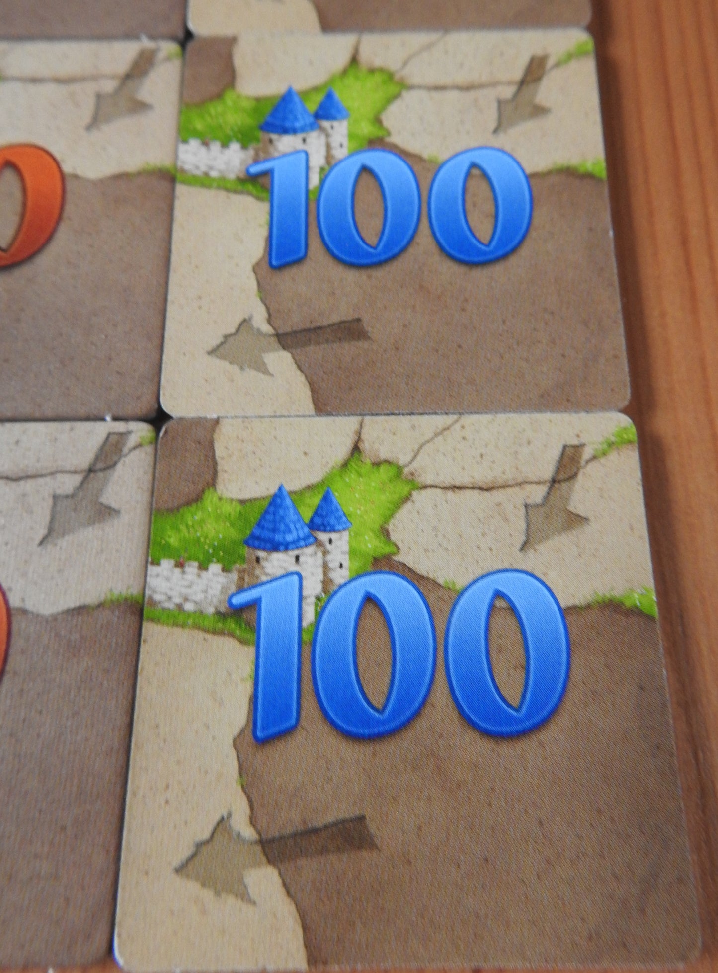 A close-up of some of the '100' tiles that come with this 6 Extra Scoring Tiles accessory for Carcassonne.