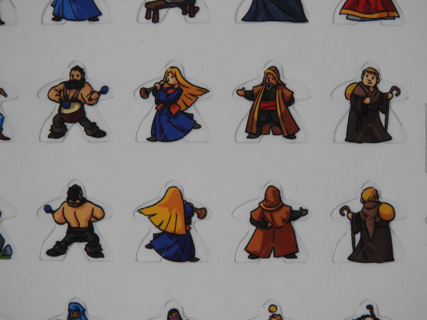 Close-up view of some of the meeple stickers, including a lady playing a pipe and a travelling monk.