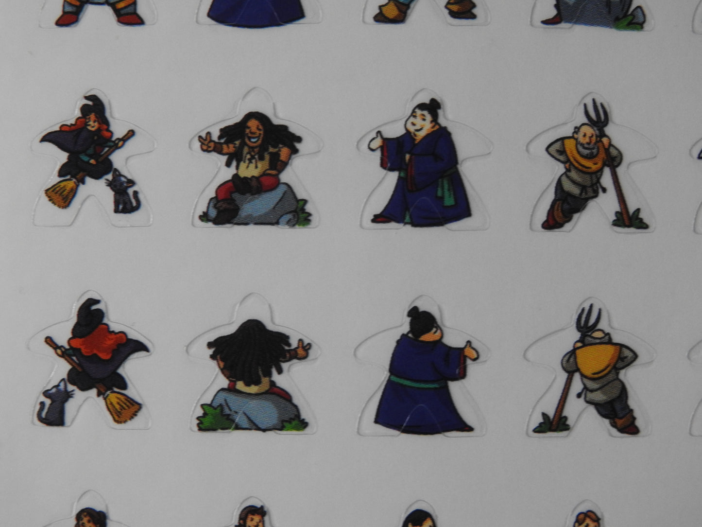 Close-up view of some of the meeple stickers, including a witch on a broomstick and a man sitting happily on a rock.