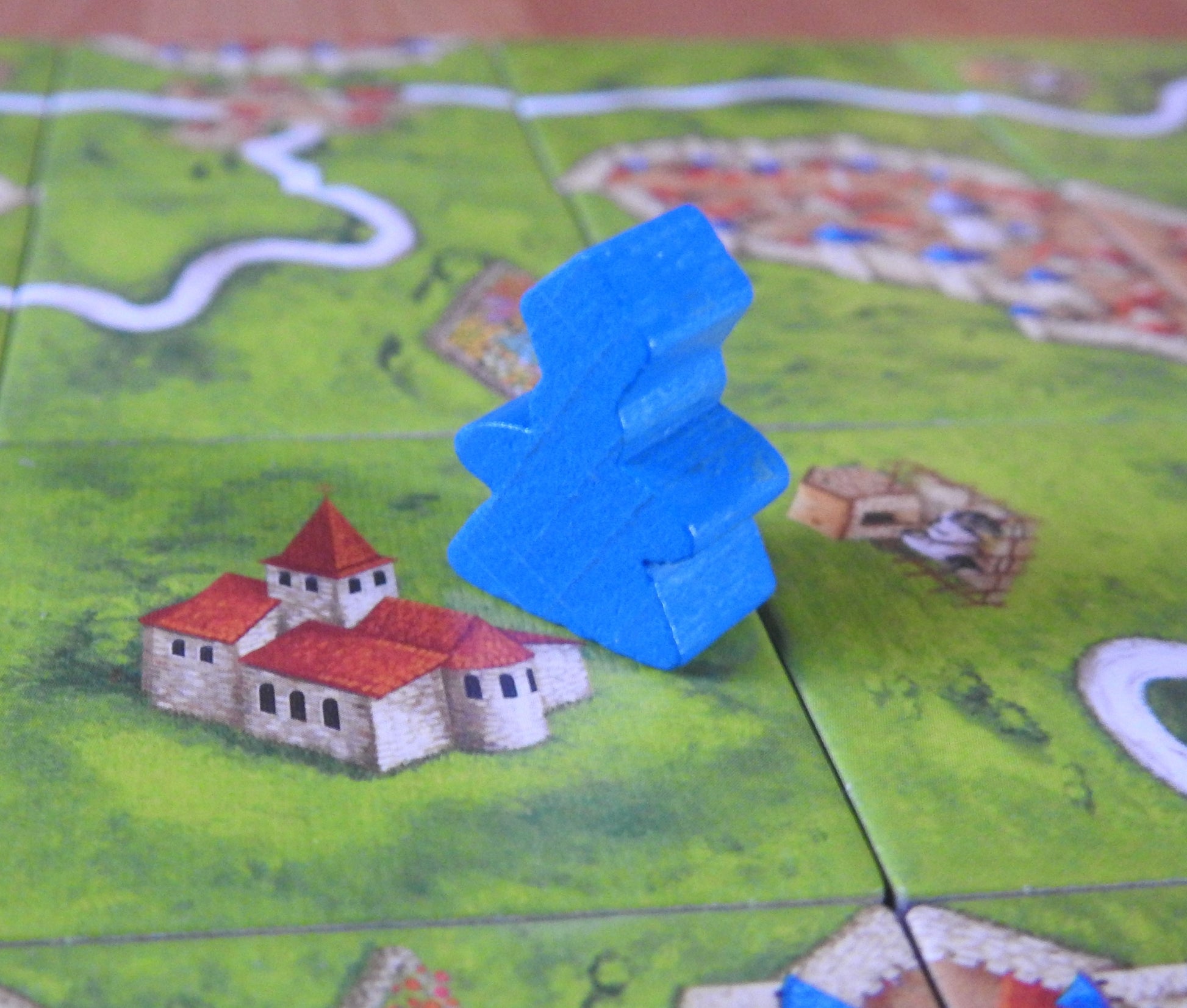 A close-up of a blue wooden abbot meeple.