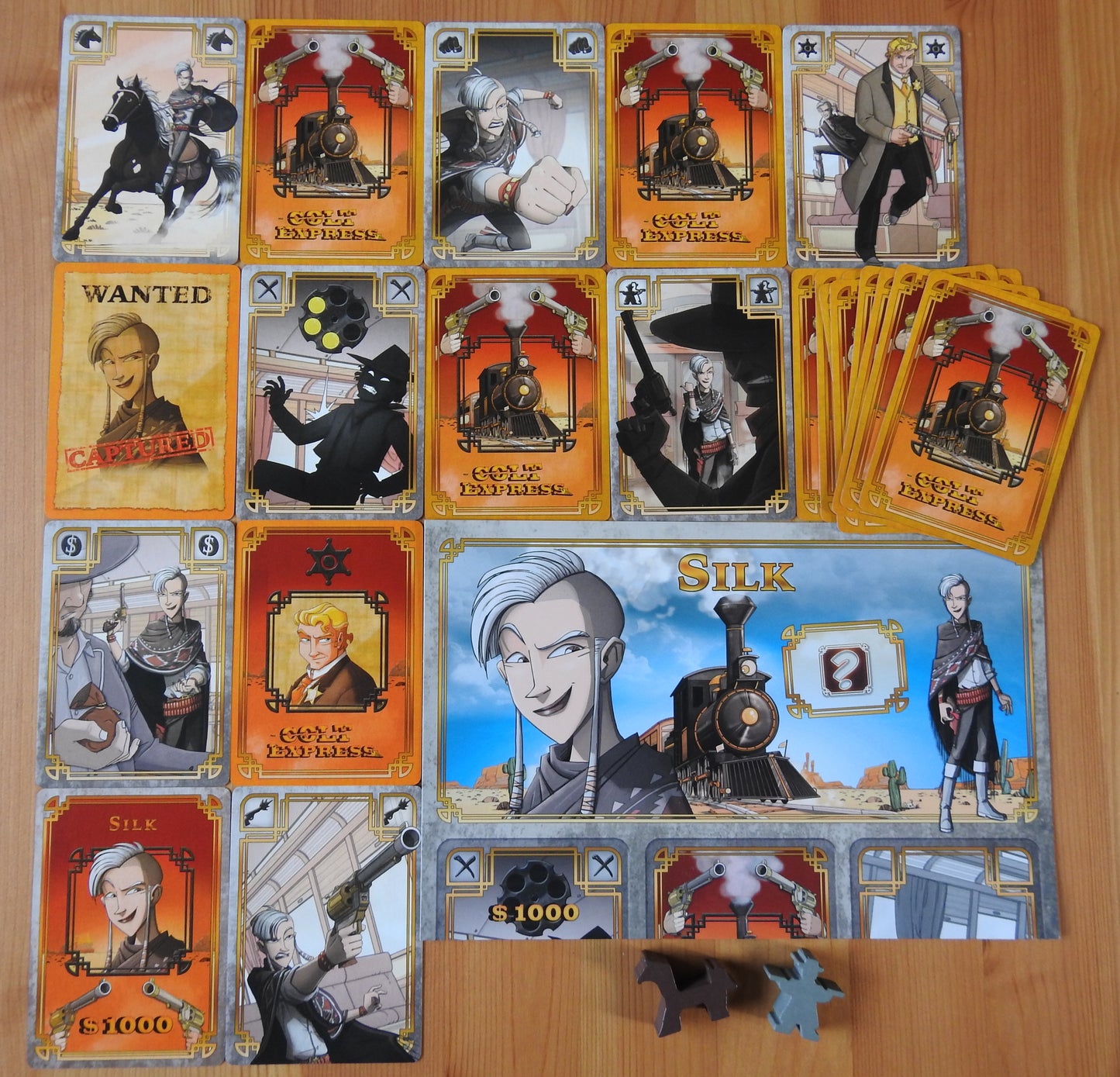 View of all the cards, sheets and wooden pieces included in the Colt Express Silk Bandit mini expansion.