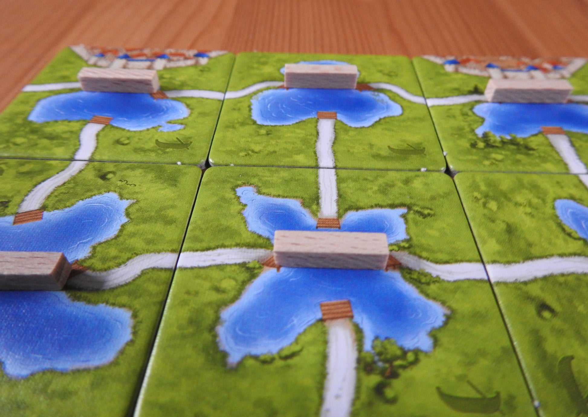 A closer view of the wooden ferry pieces on the tiles of this Carcassonne Ferries expansion.