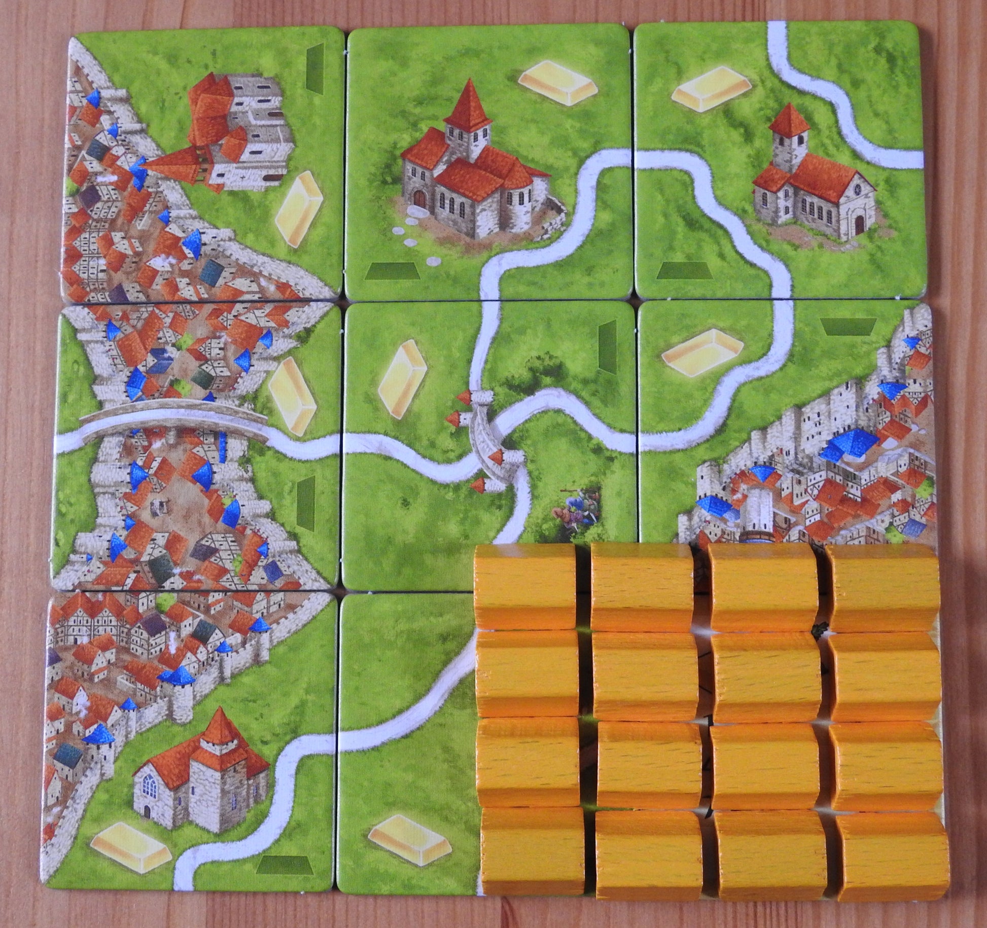 View of all the landscape tiles and wooden gold bar pieces featured in this Carcassonne Gold Mines expansion.