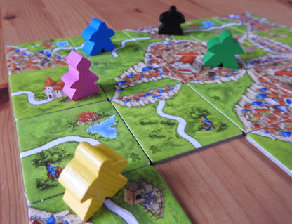 A close-up of the meeples, tiles and abbots that are included in this Carcassonne Inns & Cathedrals expansion.
