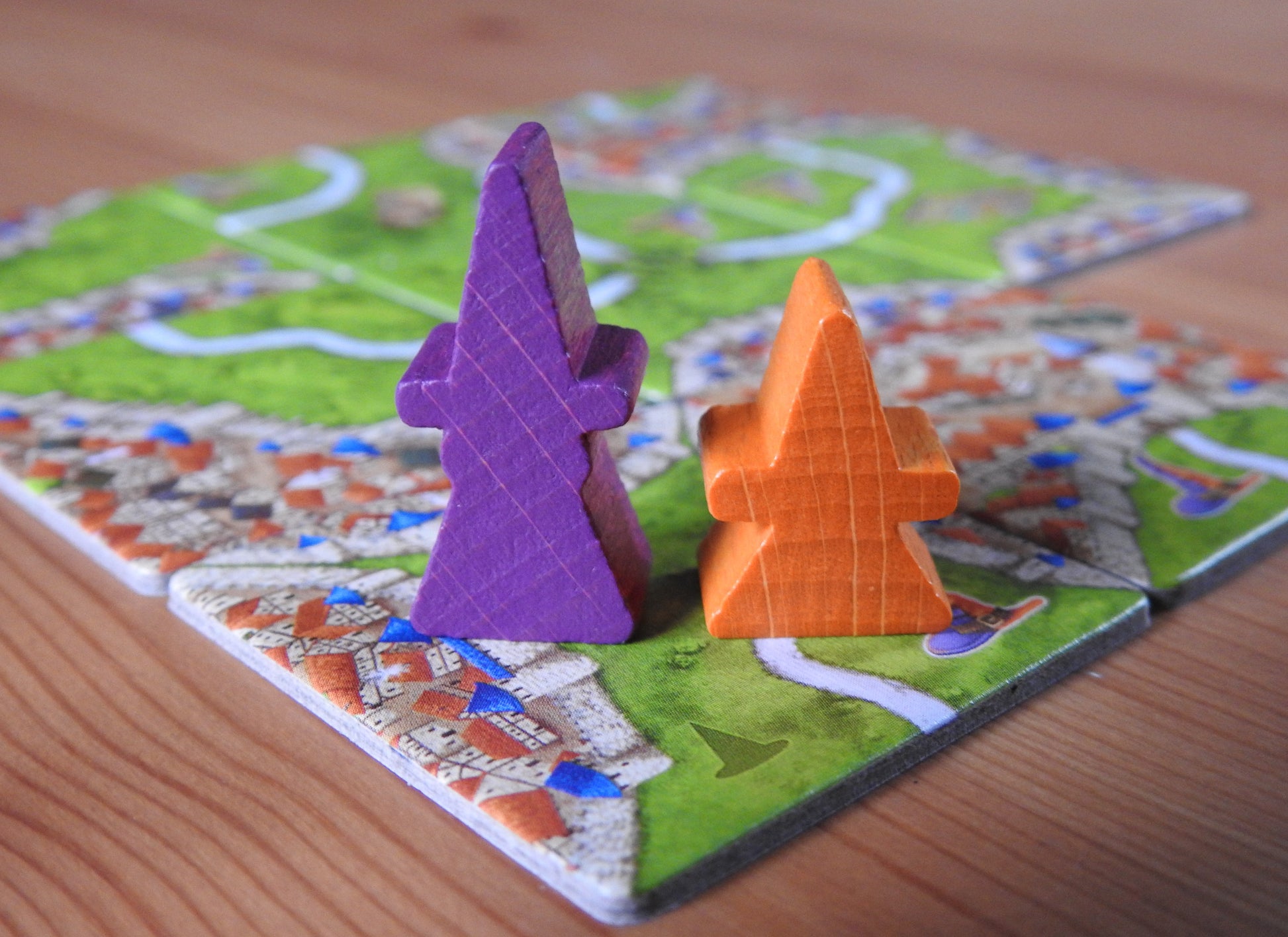 Close-up of the purple wooden witch meeple and the orange mage figure that are included in this Carcassonne Mage & Witch expansion.