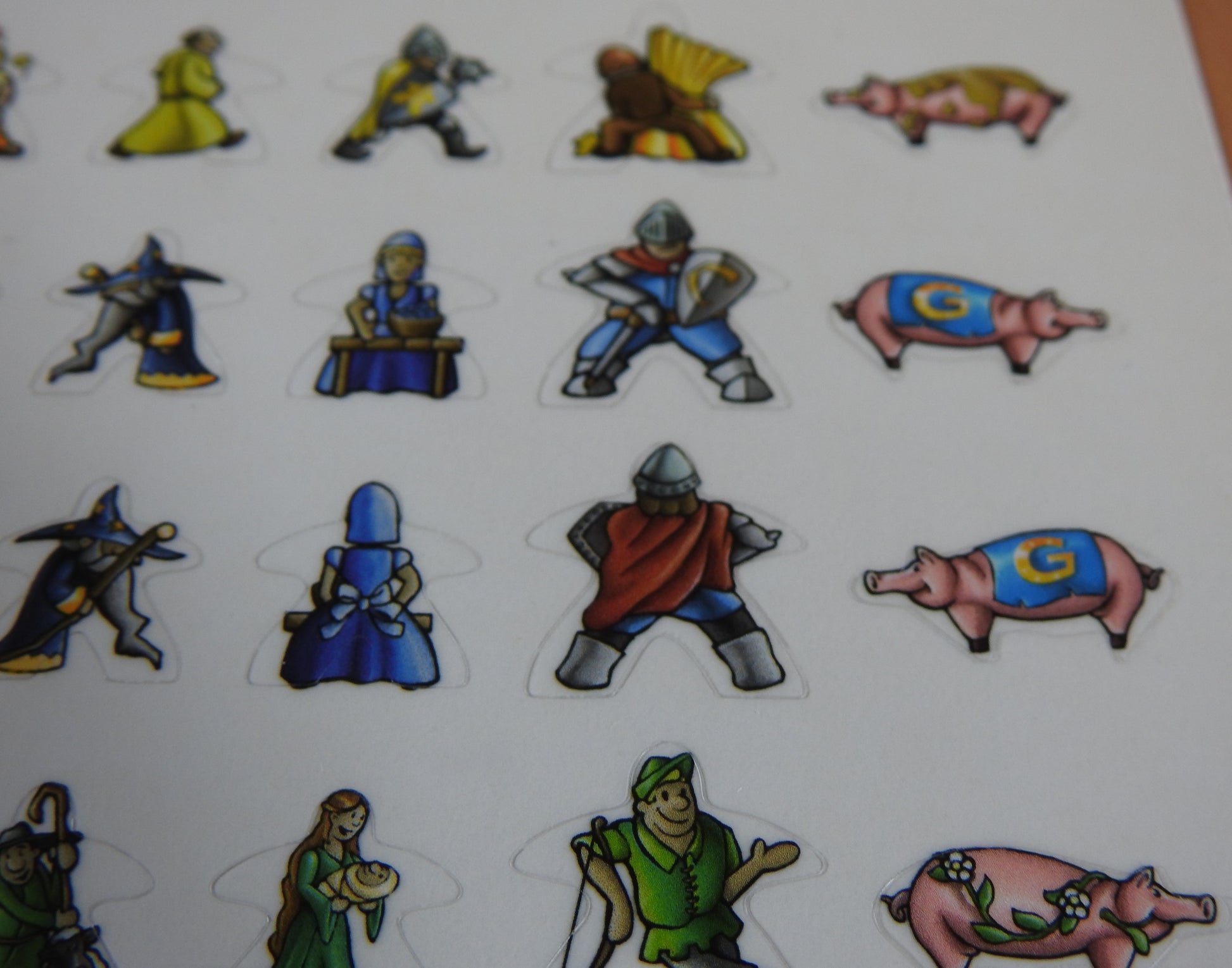Close-up of four rows of Carcassonne meeple stickers, showing pigs and medieval knights!