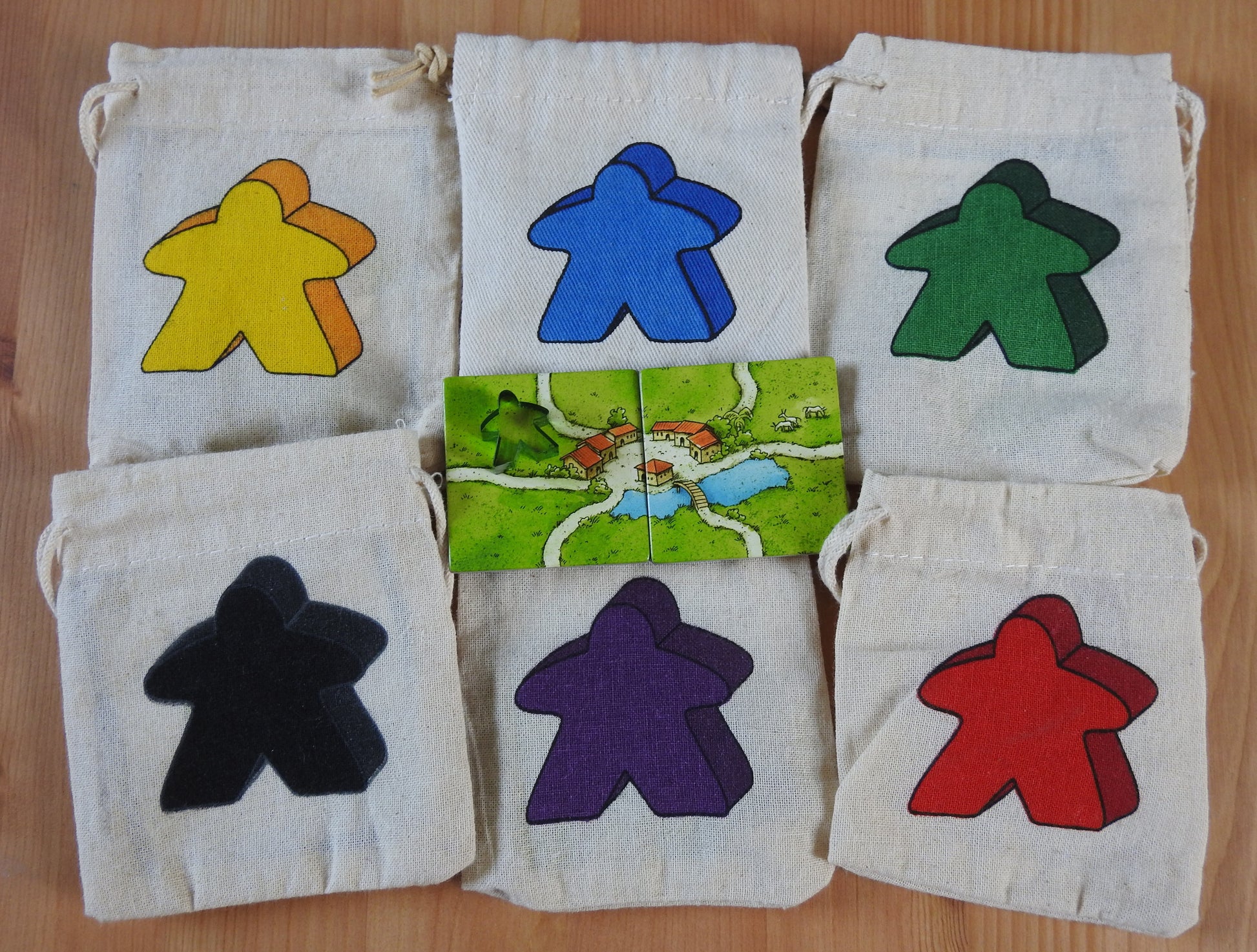 Top view showing all 6 Meeple bag colours and the 2 tiles and teacher meeple that come with this School Carcassonne Mini Expansion.