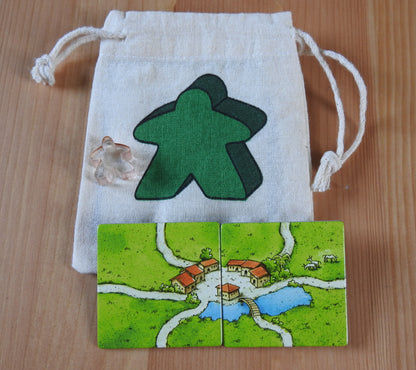 Close-up of the green meeple bag, red meeple teacher and 2 tiles.