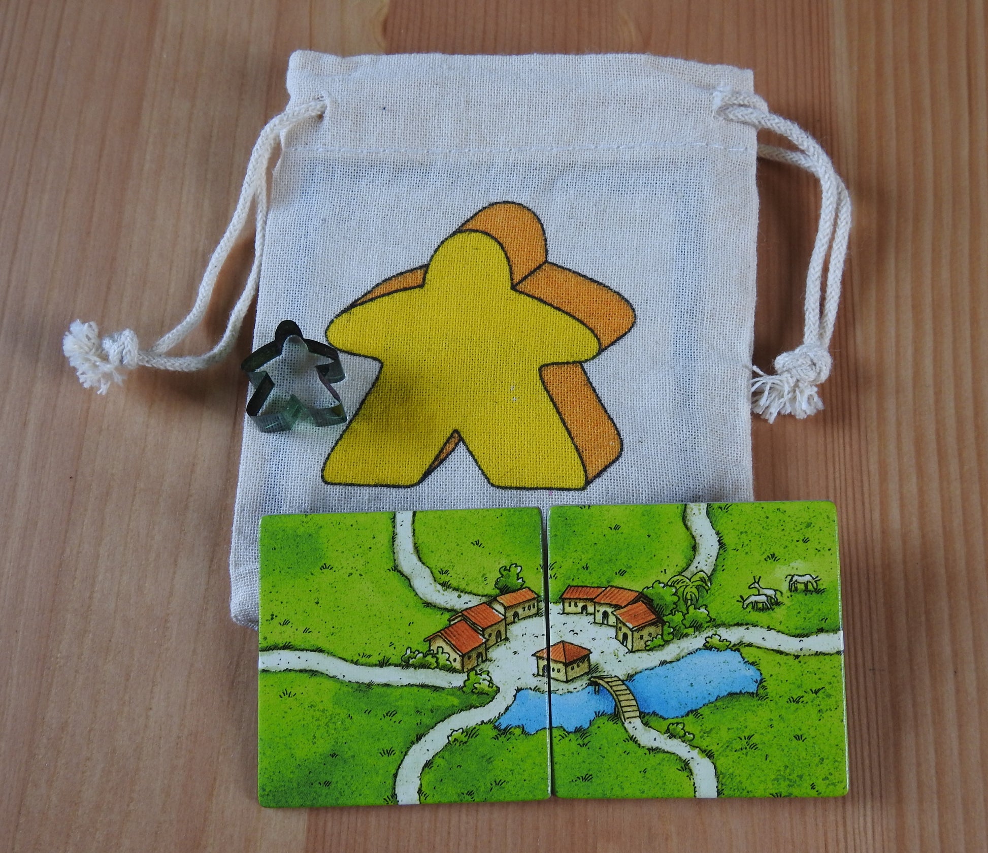 Close-up of the yellow meeple bag, green meeple teacher and 2 tiles.