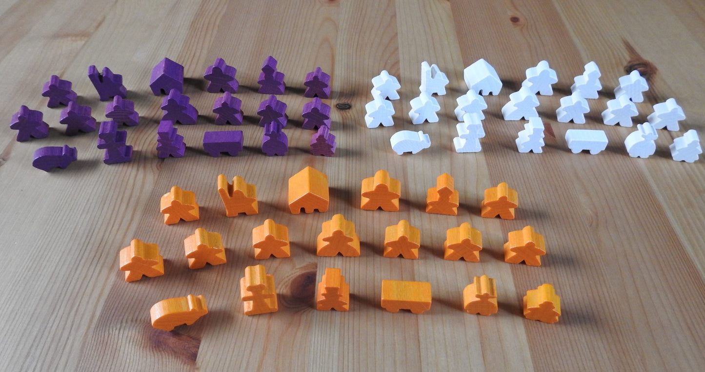 Top view of 3 of the differenet wooden meeple set colours available - orange, purple and white.